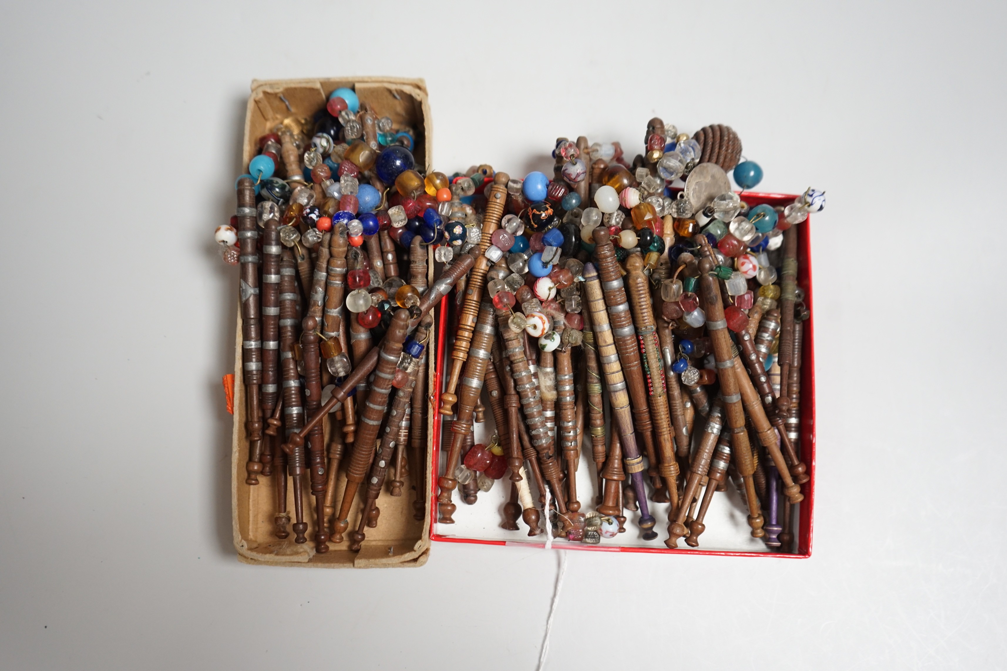 Eighty 19th century wood and metal decorated lace bobbins with coloured beaded tops